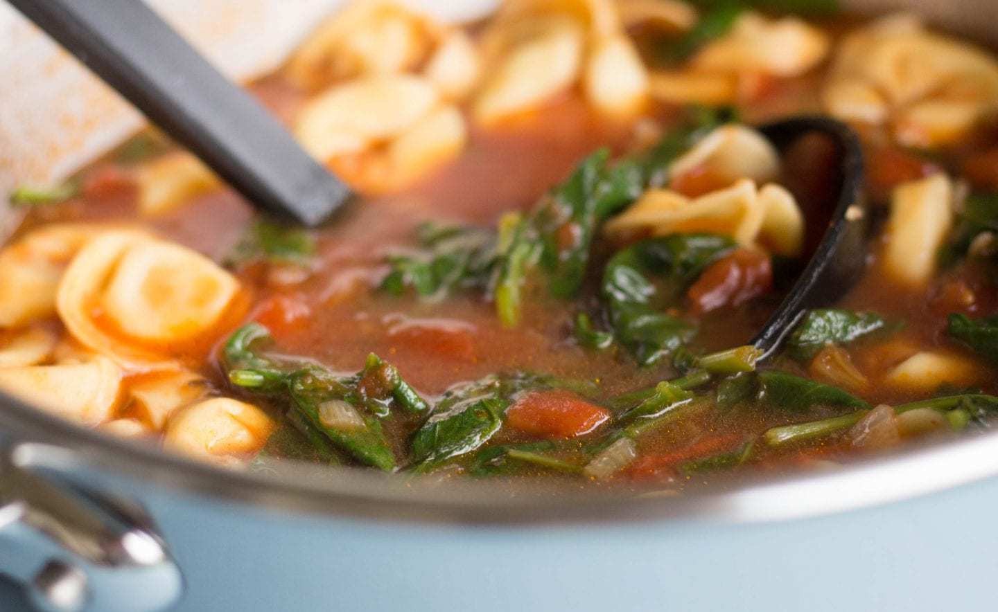 Pot of tortellini soup with ladle