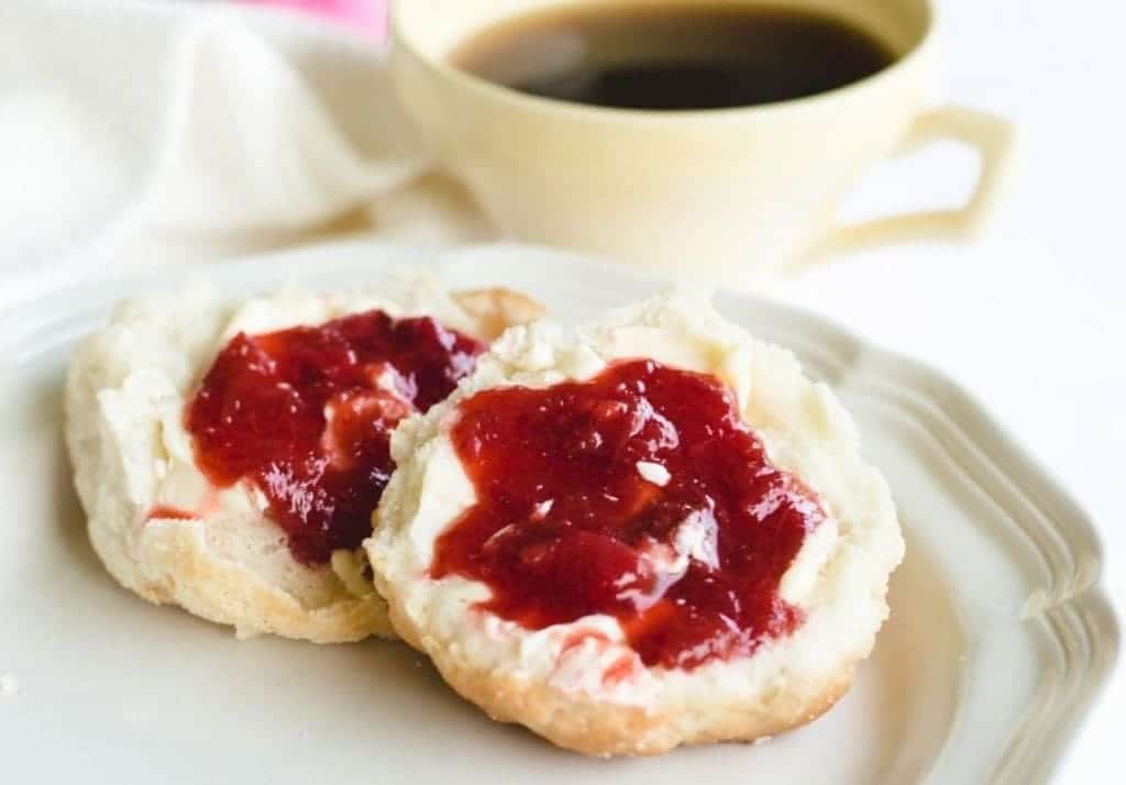 homemade biscuits topped with strawberry rhubarb jam on white plate
