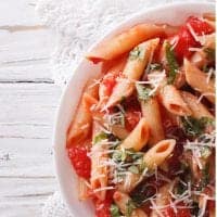 Penne Arrabbiata topped with parmesan on white plate