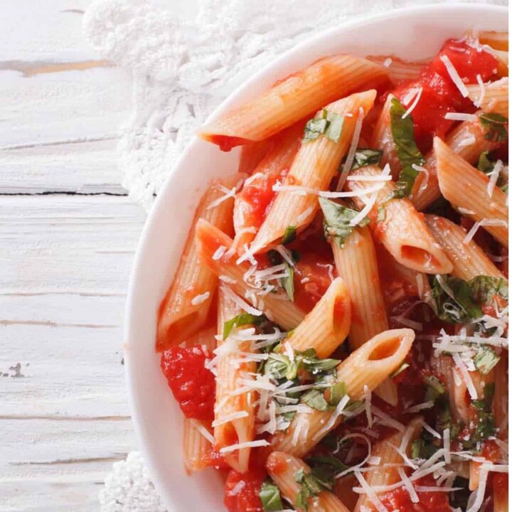 Penne Arrabbiata topped wioth parmesan on white plate