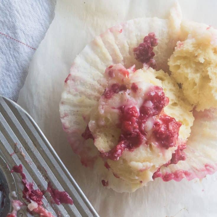 raspberry cream cheese muffin on table next to muffin tin