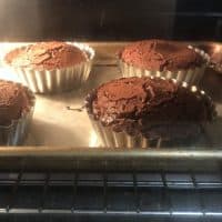 Individual chocolate cakes baking in countertop oven.