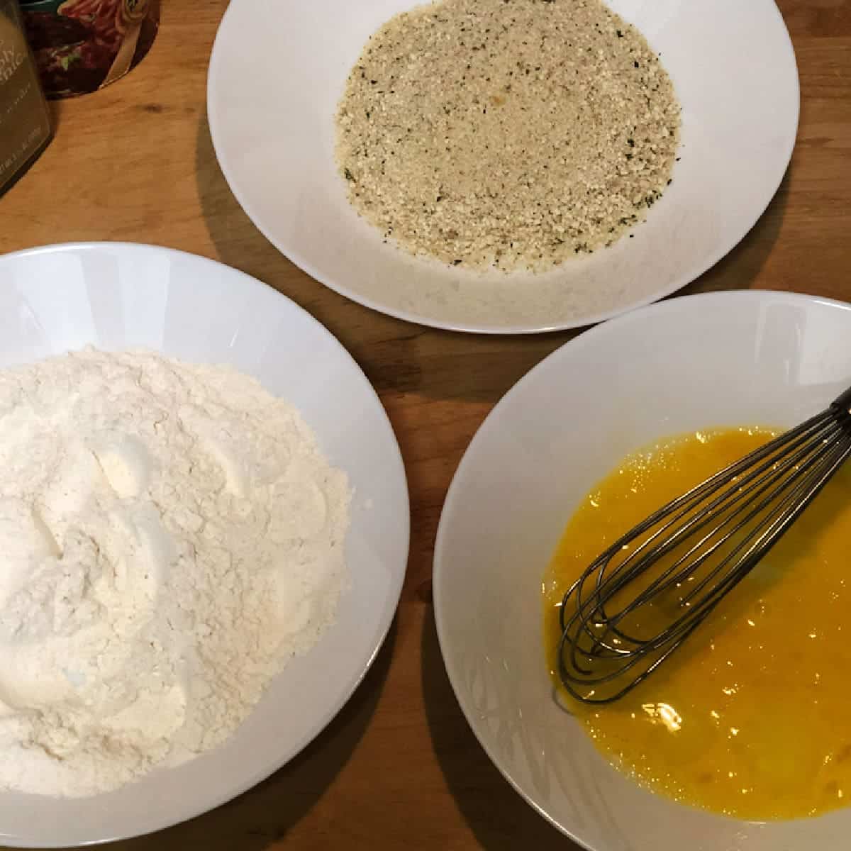 flour, egg, and bread crumbs in shallow bowls for dredging chicken.