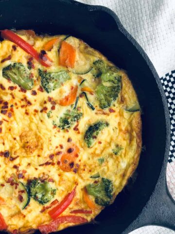 close up view of vegetable frittata in cast iron skillet.