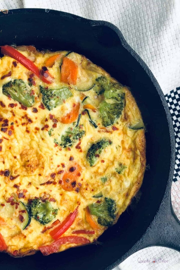close up view of vegetable frittata in cast iron skillet.