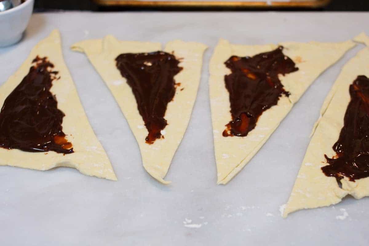 puff pastry triangleswith chocolate sauce sprad over.
