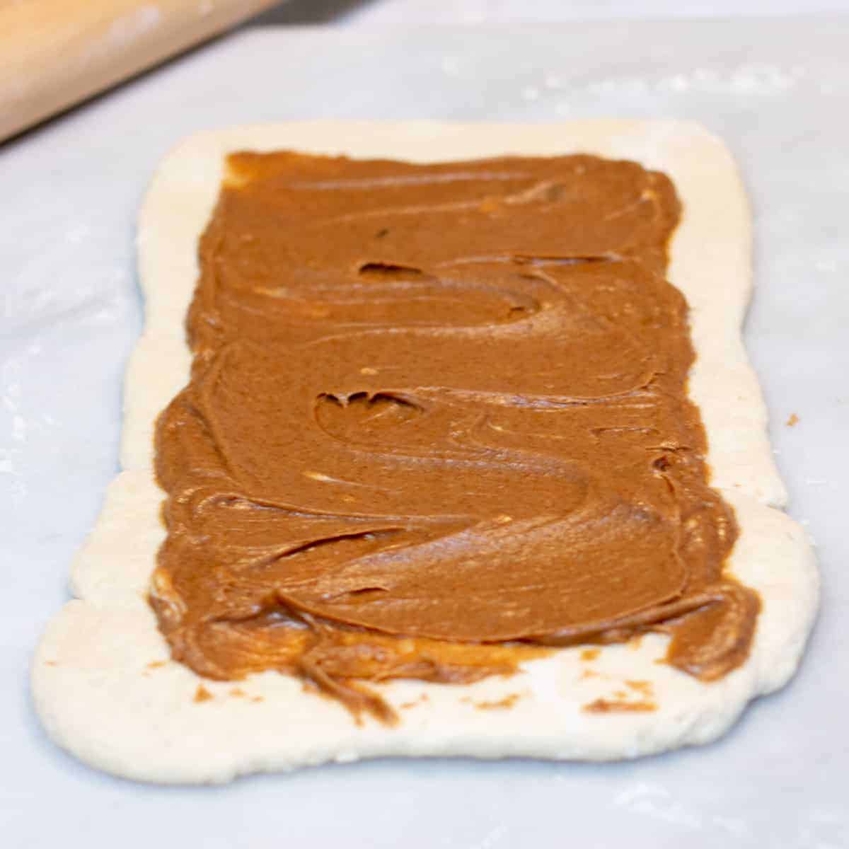 cinnamon roll filling spread over rolled out biscuit dough.