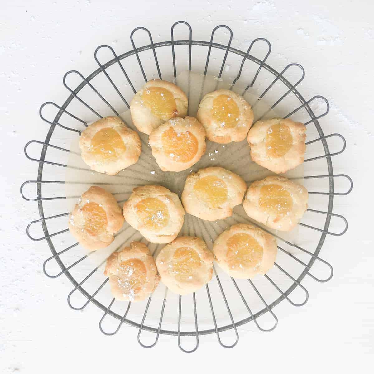 a dozen lemon curd thumbprint cookies on wire cooking rack.