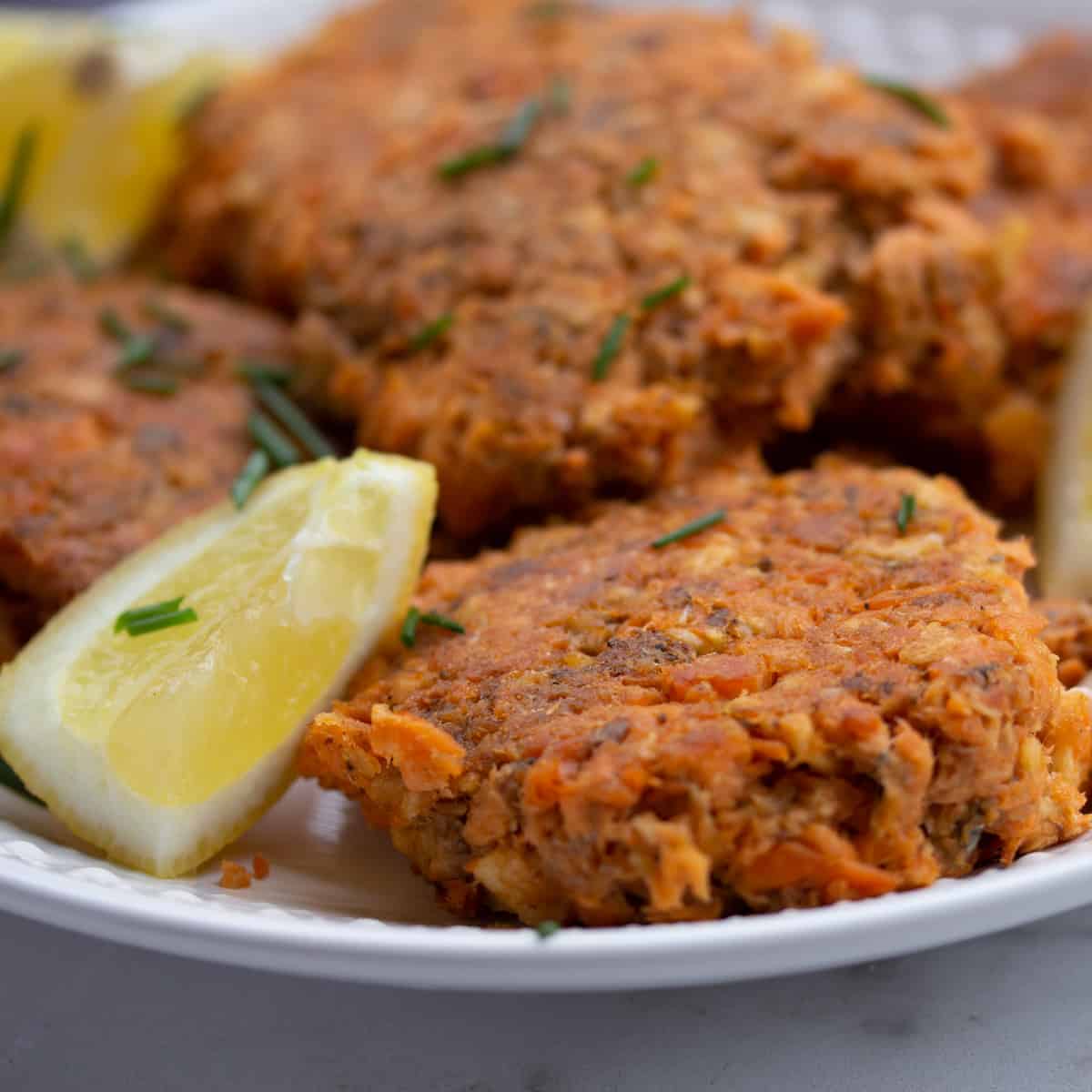 pan fried salmon paties on plate with lemon wedge.