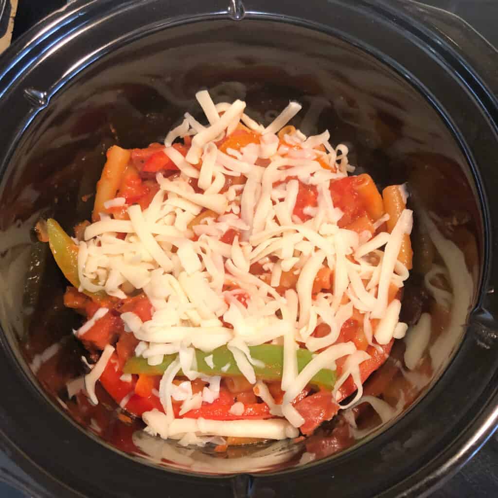 sausage and peppers recipe topped with mozzarella in 3-quart slow cooker.