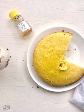slow cooker cornbread with one slice missing on white plate.