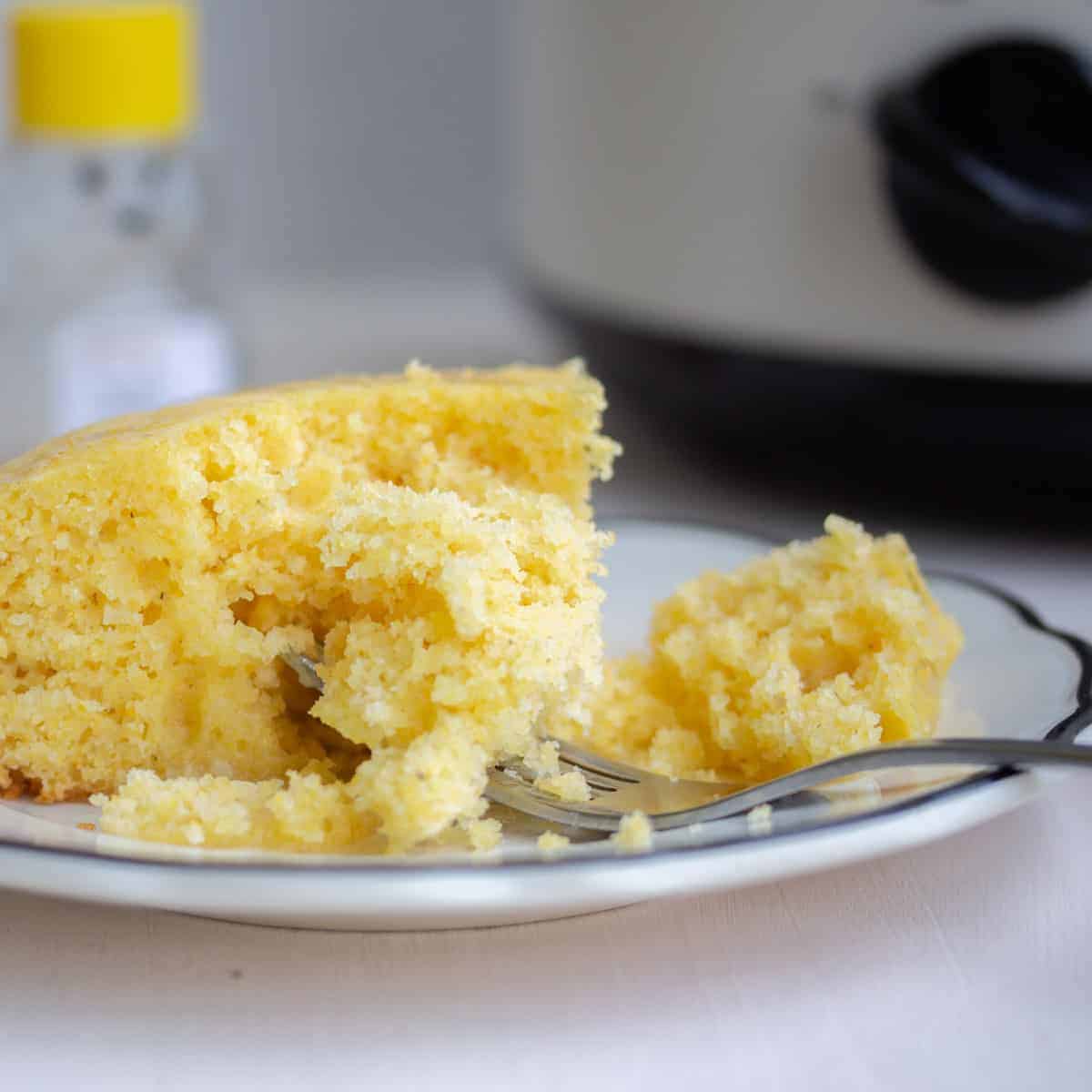 closeup pf cornbread on plate with slow cooker in background.