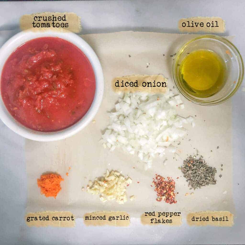 ingredients to make slow cooker marinara sauce on parchment lined marble board.