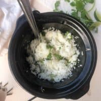 cooked cilantro rice in slow cooker with metal sppon.
