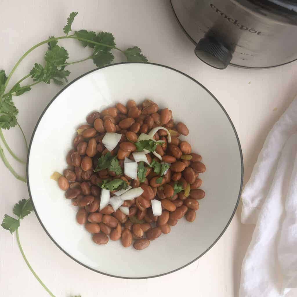 bowlof pinto beans topped with onions and fresh cilantro.