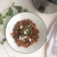 bowl of pinto beans topped with onions and fresh cilantro.