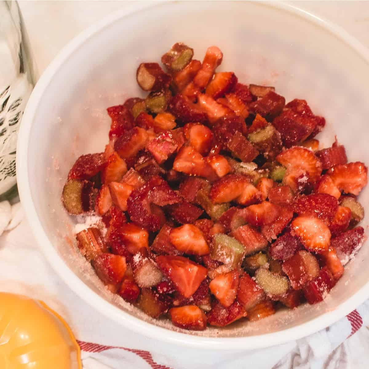 chopped fresh rhubarb and fresh strawberries sprinkled with sugar in large bowl.