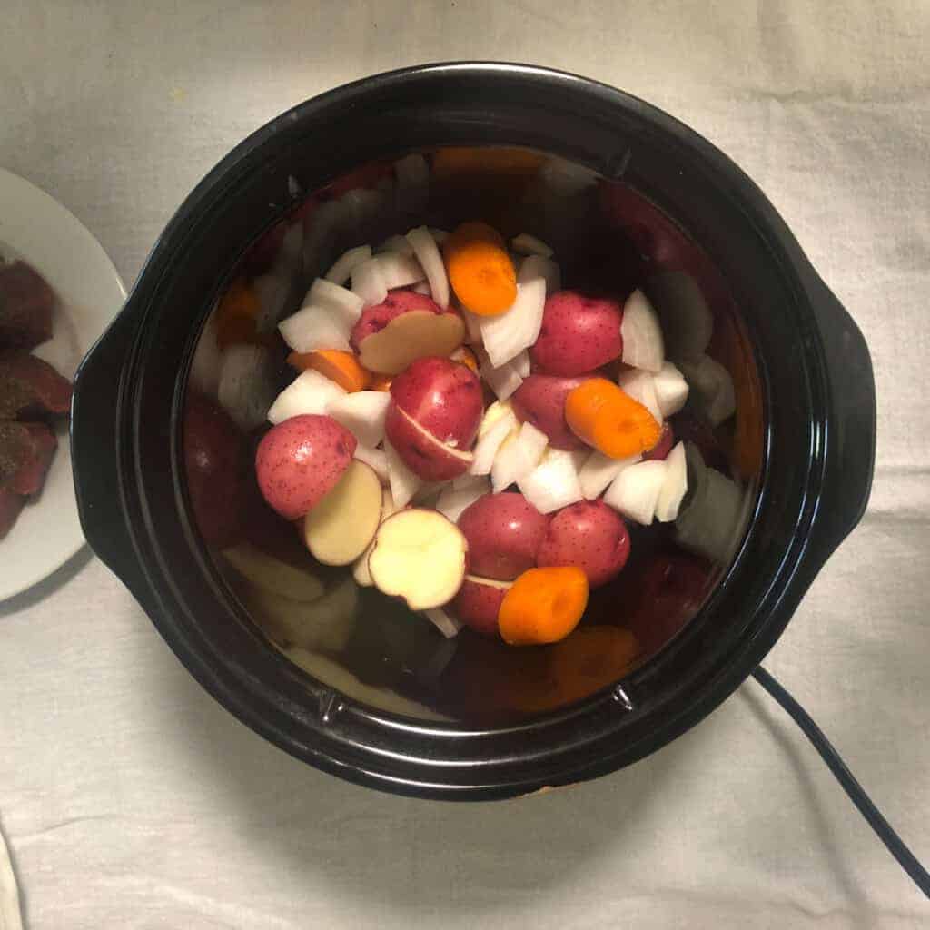 Onions, potatoes, carrots in slow cooker.