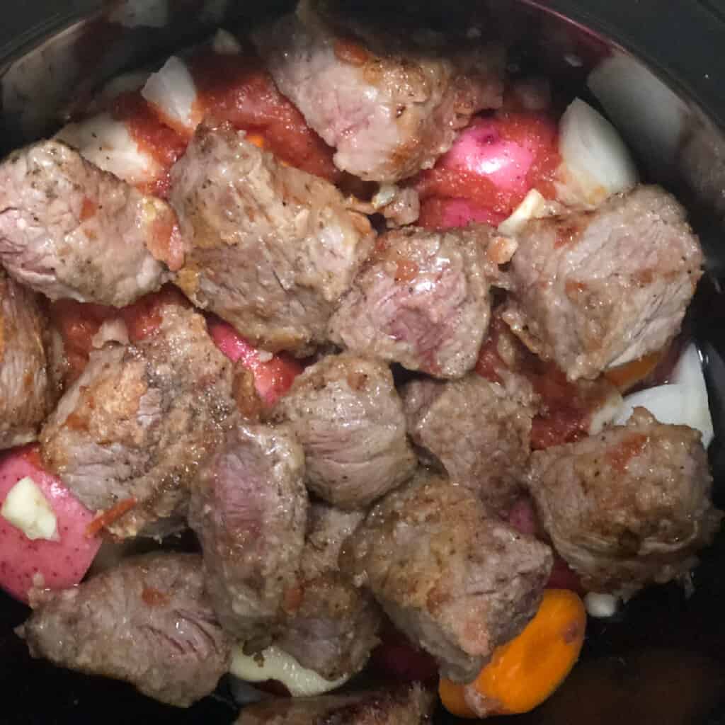 Chunks of stew meat in slow cooker.