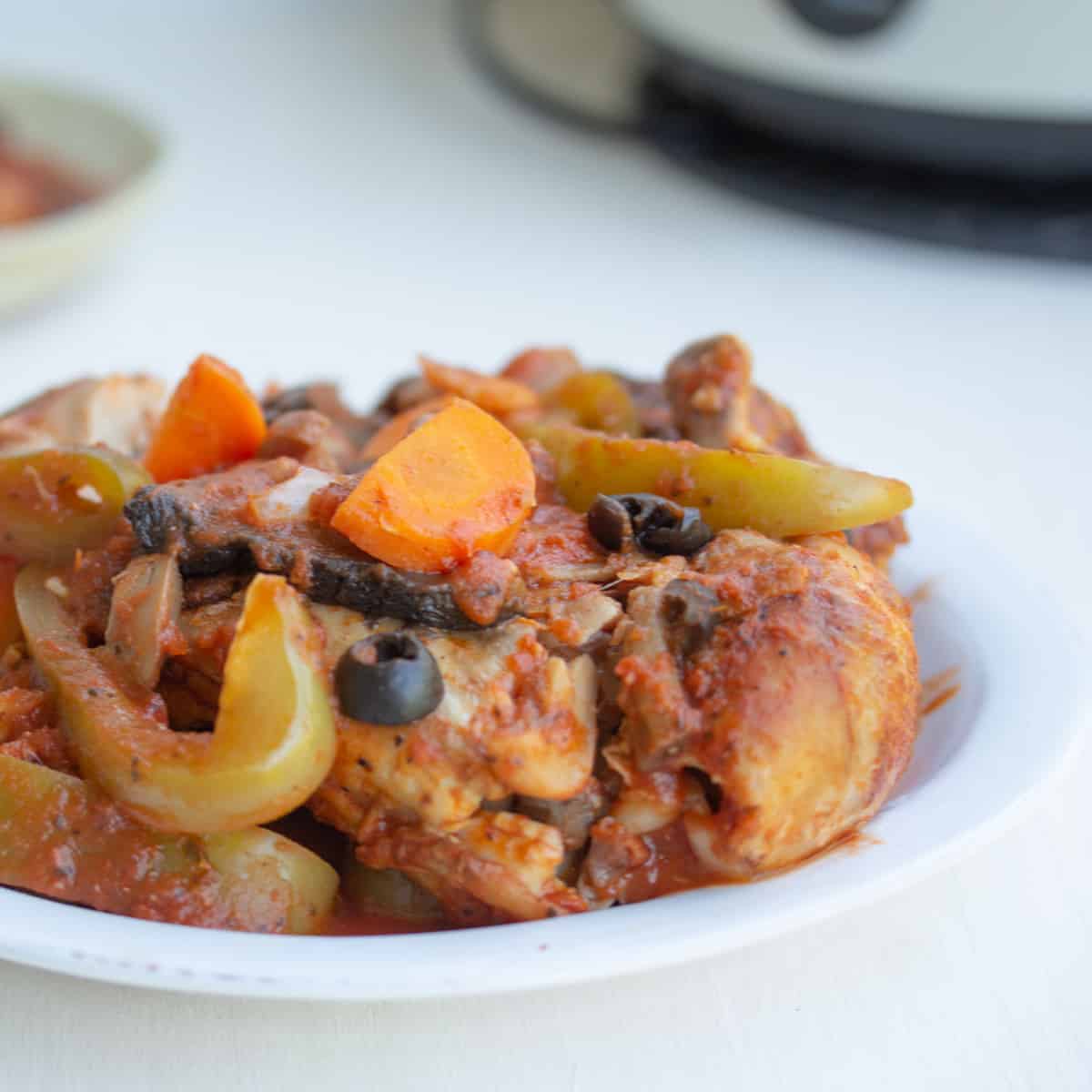 plate of chicken cacciatore with slow cooker in background.