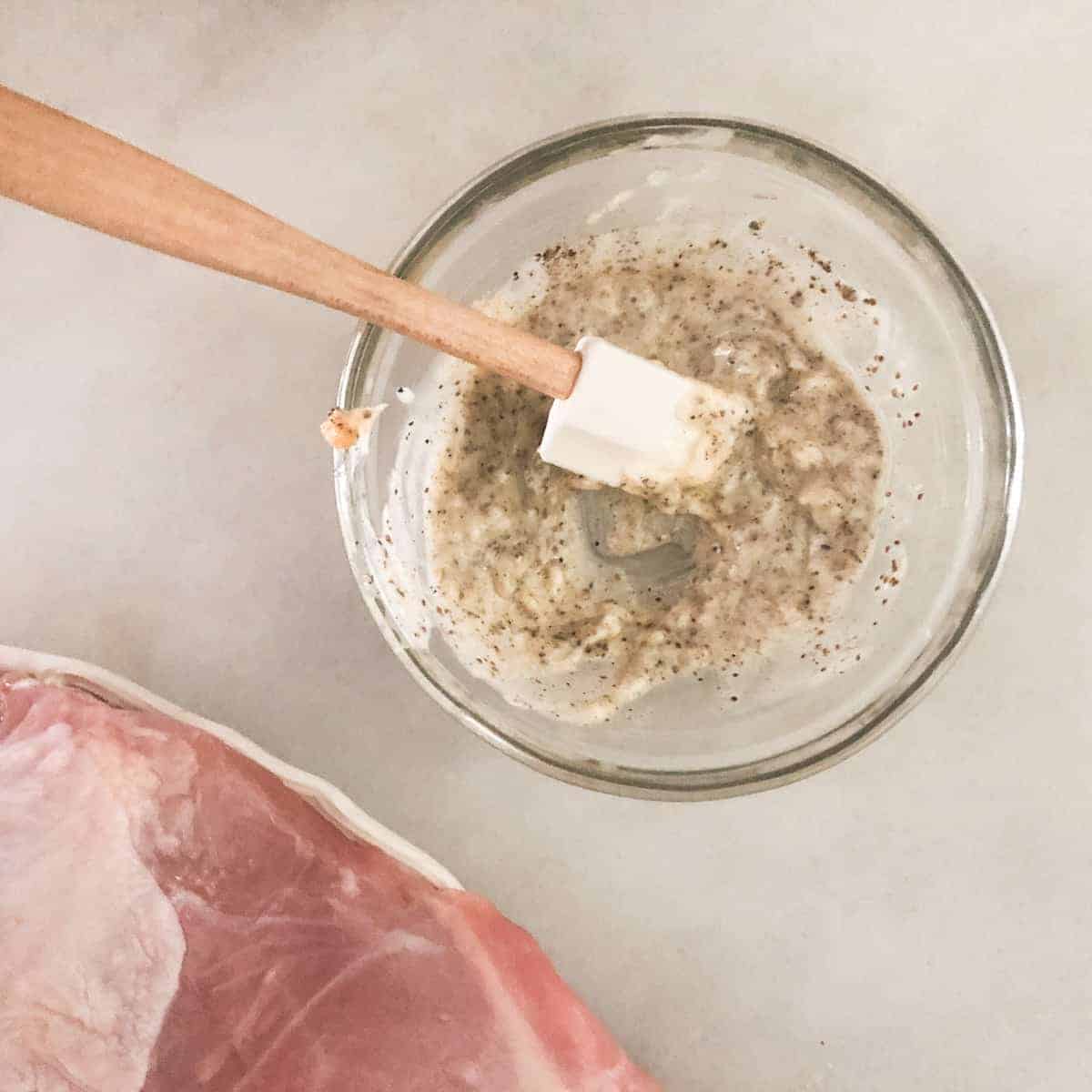 soft butter mixed with seasoning in clear bowl with small spatula.