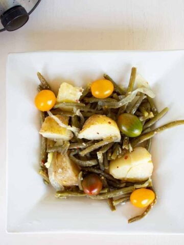 green beans and potatoes on square wwhite plate.
