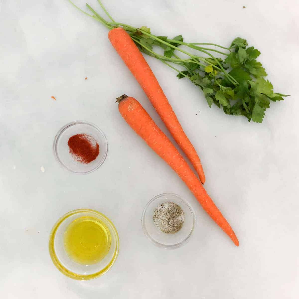 Carrots, seasoning and olive oil on countertop.