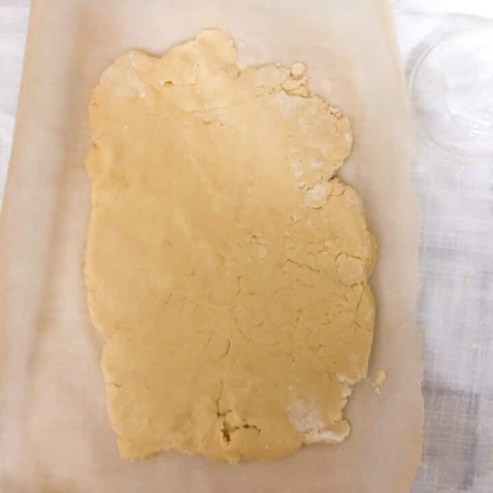 Rolled out shortbread cookie dough on parchment paper.