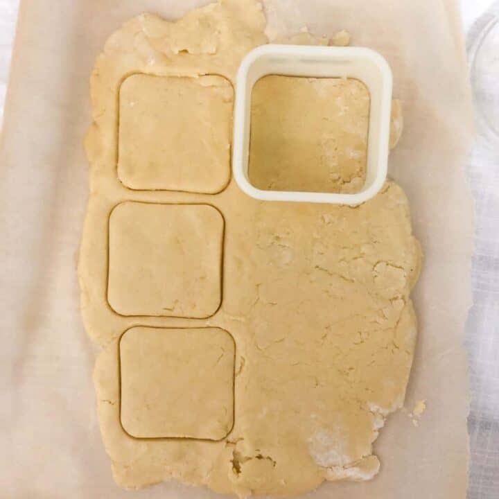 Rolled out cookie dough with square cookie cutter.