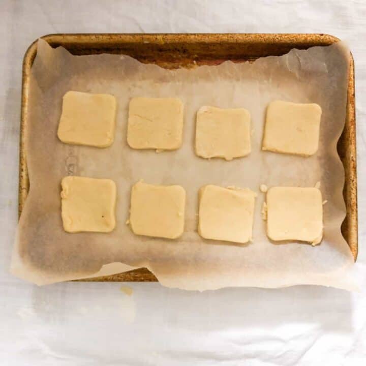 Unbaked cut out shortbread cookies on parchment lined baking sheet.