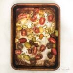 Roasted grape tomatoes on parchment lined baking sheets.