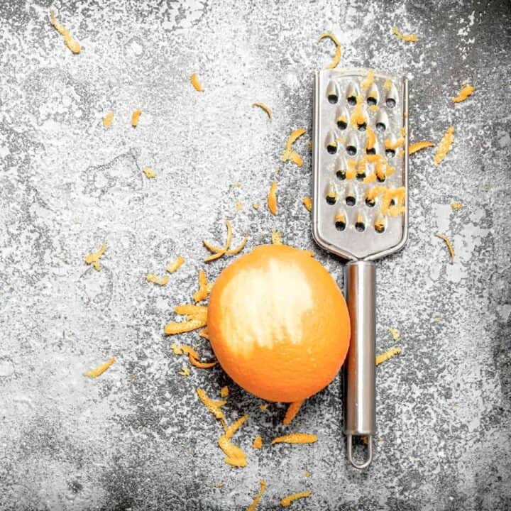small grater and zested orange on concrete table.