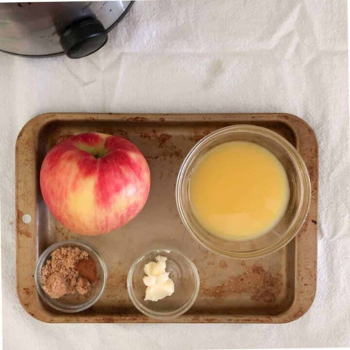 Butter, cinnamon, orange juice and apple on baking sheet.