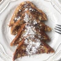 Plate of french toast cut into triangle and dusted with powdered sugar.