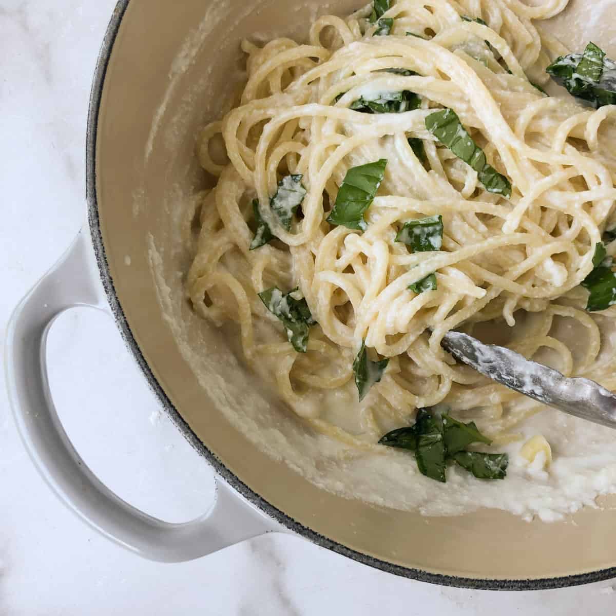 Lemon ricotta spahettin in small grey le crueset pan.