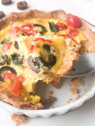 Quiche in tart pan with fork.