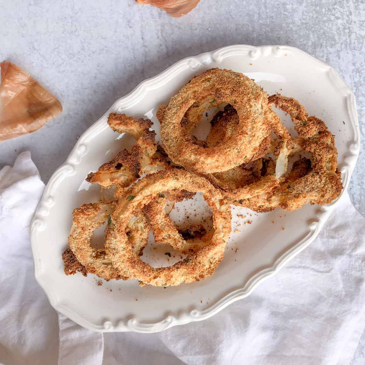 Baked onion rings on white oval plate.