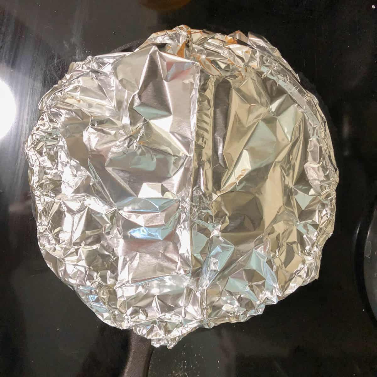 Foil tent over pot roast in cast iron skillet.