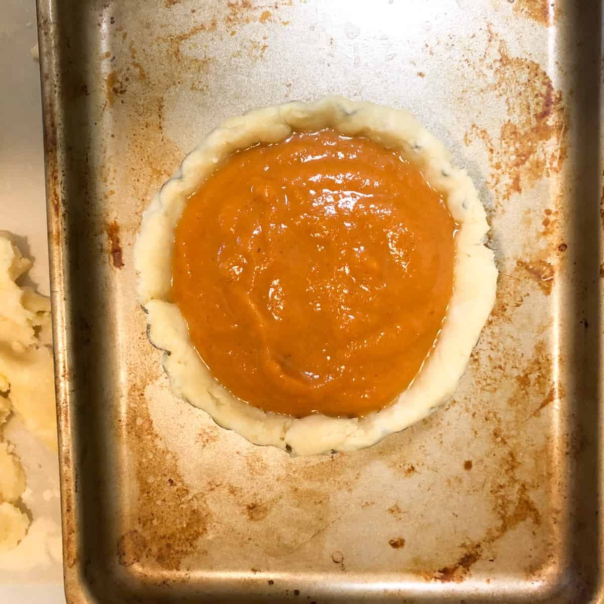 Unbaked pumpkin pie on baking sheet.