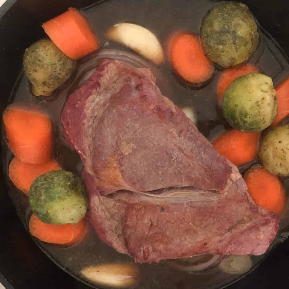 Pot roast with brussel sprouts, carrots , and beef broth n cast iron skillet.