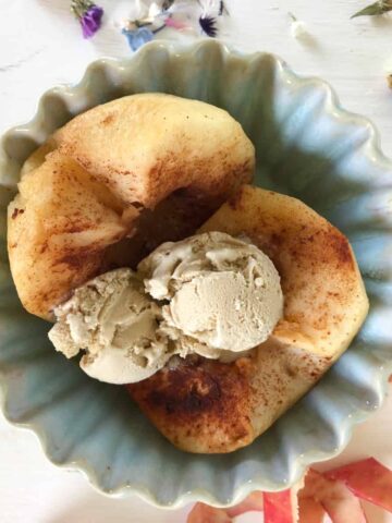 Baked apple and ice cream in blue bowl.