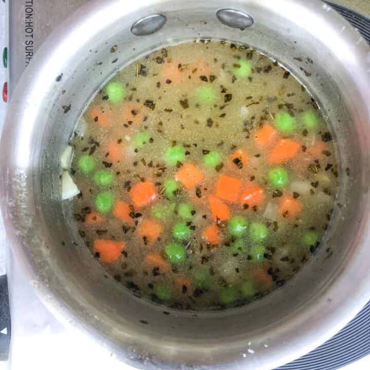 Carrots and peas simmering in chicken broth.