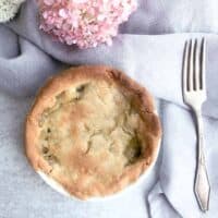 individual chicken pot pie baked in white dish on table with pink flowers