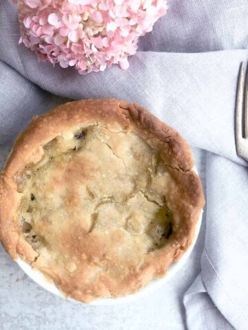 individual chicken pot pie baked in white dish on table with pink flowers