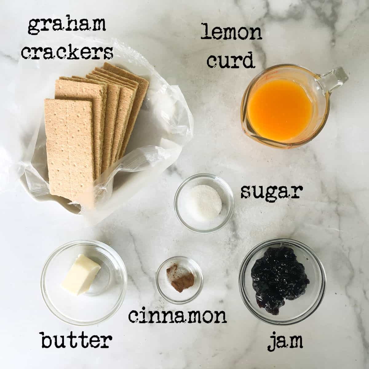 graham cracker sheets, lemon curd, butter, cinnamon and blackberry jamin clear bowls on marble surface.