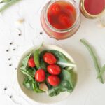 Bowl of pickled tomatoes on bed of spinach.