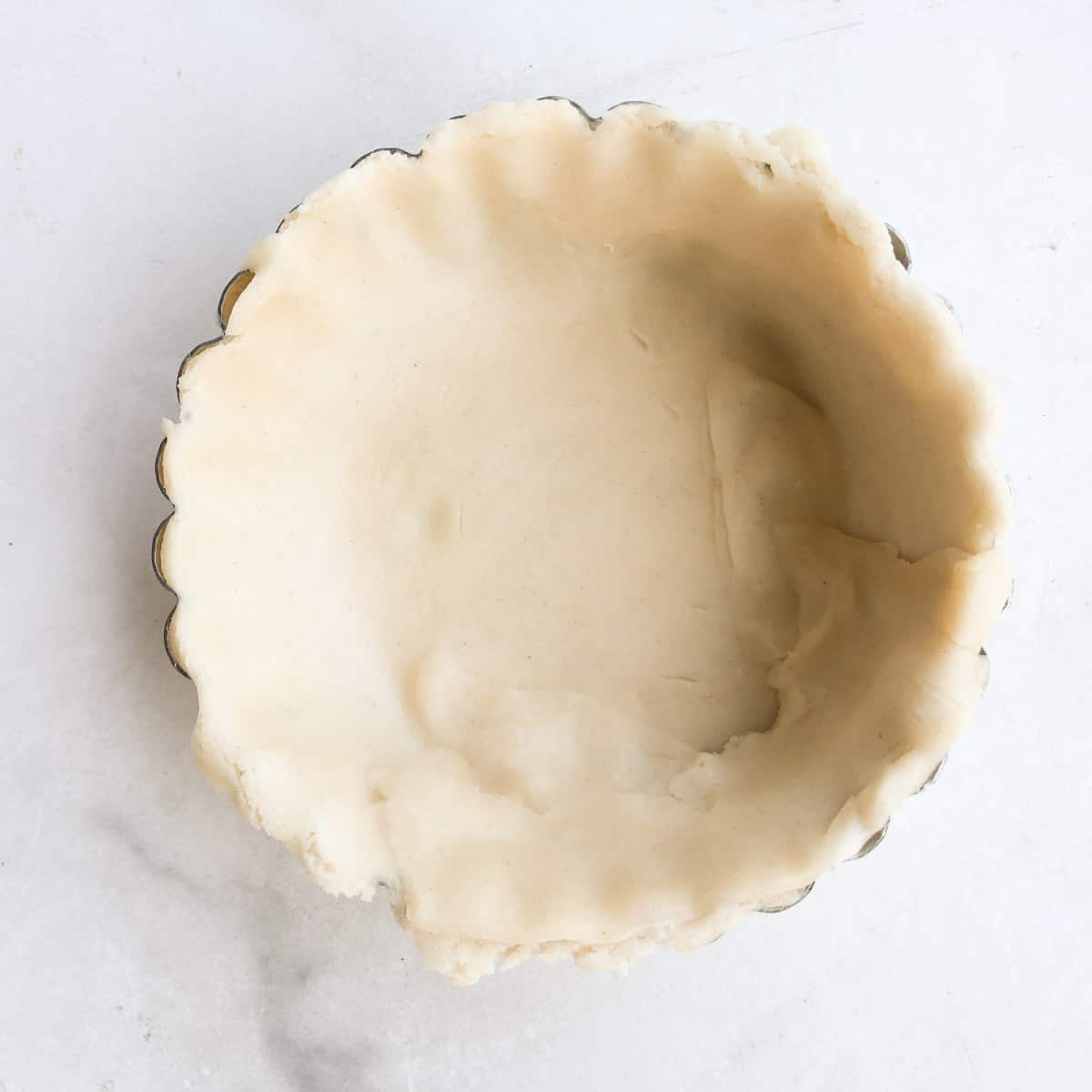 Unbaked pie crust in 4-inch tart pan.