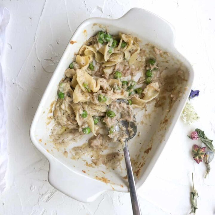 Tuna casserole in small white baking dish with serving spoon.