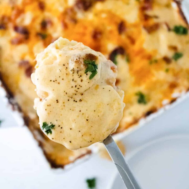 spoonfull of scalloped potatoes over a casserole dish.