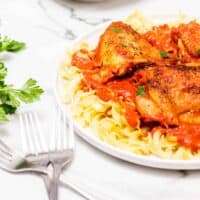 Plate of spicy chicken on bed of pasta.